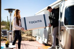 couple carrying new tochta mattress box into rv