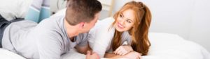 couple smiling and lying on bed