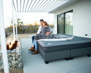 couple cuddling under blanket outside on divini mattress