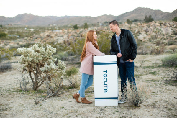 couple leaning on tochta mattress box in desert